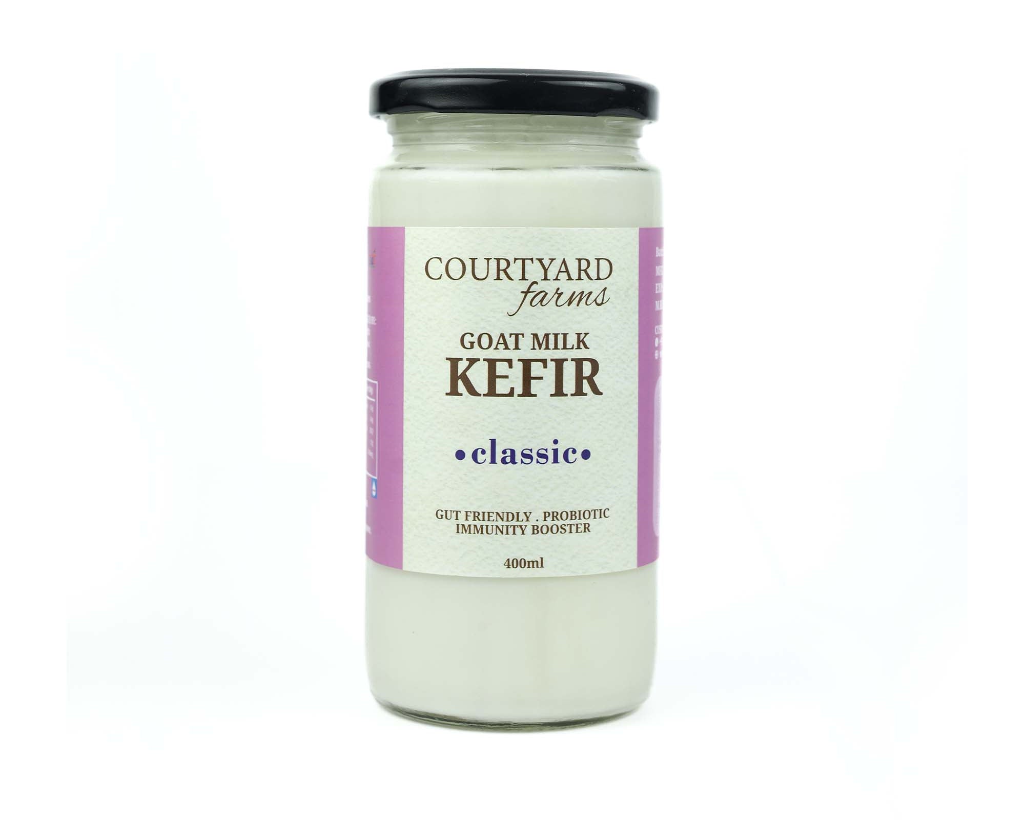 A glass bottle of Courtyard Farms Goat Milk Kefir, labeled 'Classic' with a purple and pink label.